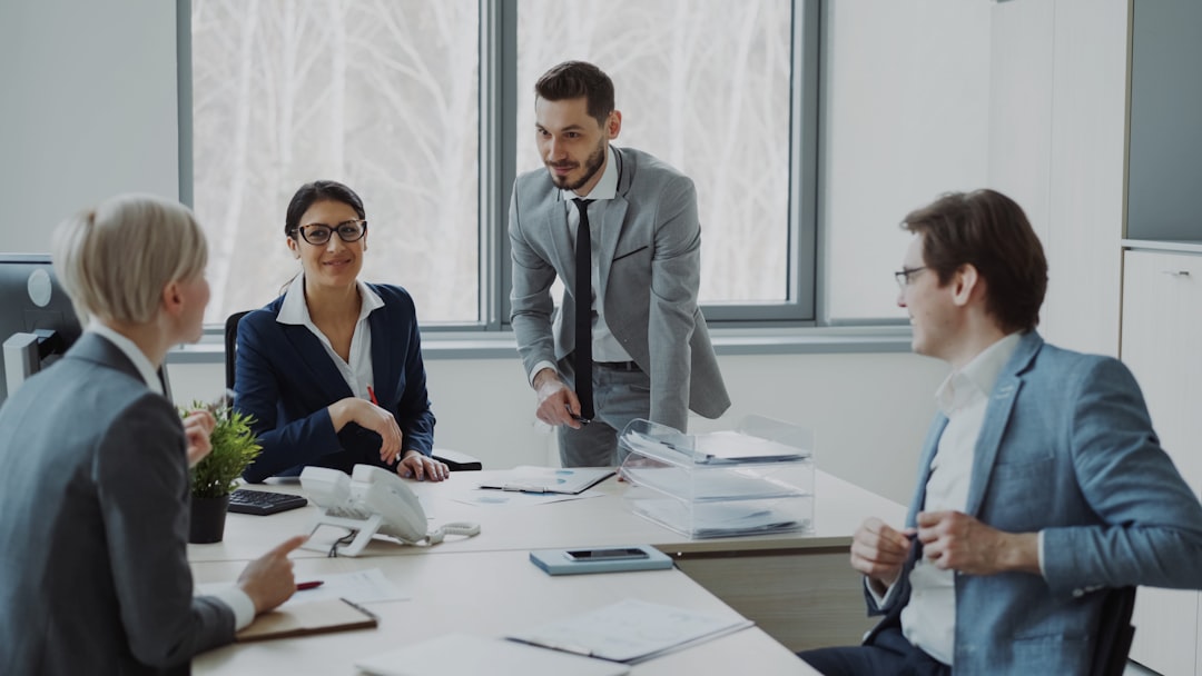 Businesswoman discussing reports with male and female colleagues sitting at the table in modern office indoors